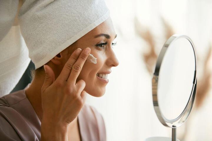 happy woman applying skincare product on her face